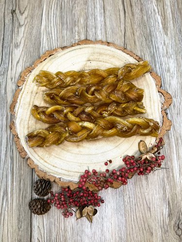 four braided beef tendons on a wooden plate