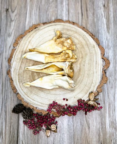 four lamb ear dog treats on a wooden plate