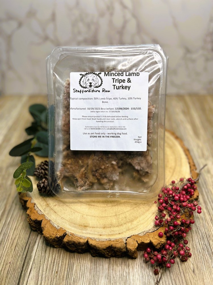 A pack of Staffordshire Raw Minced Lamb, Tripe & Turkey dog food on a wooden plate